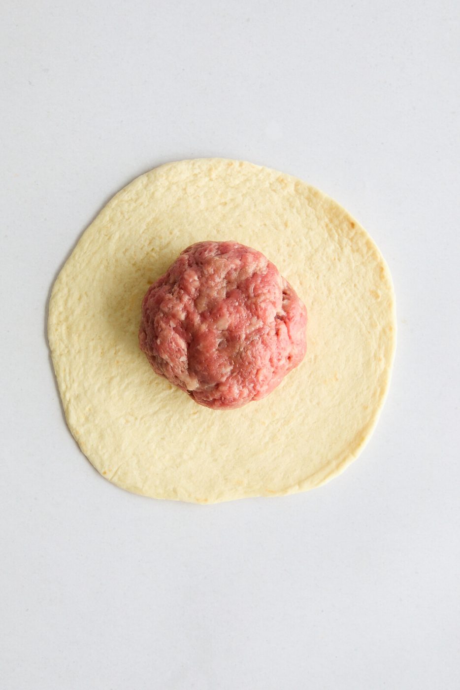An image of the tortilla with a ball of meat on top 