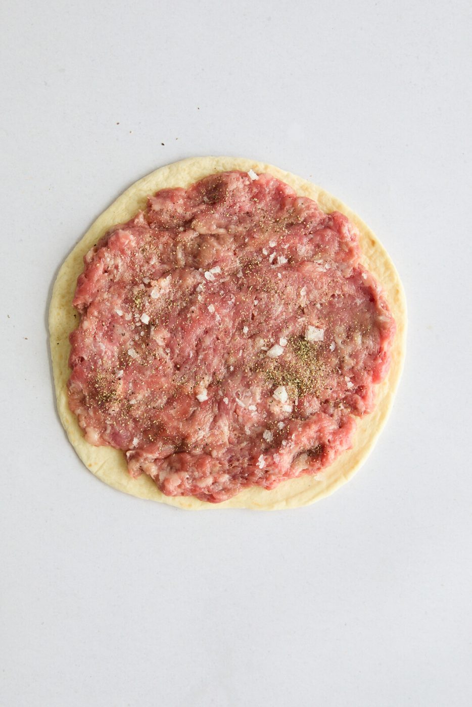 An image of the meat pressed onto the tortilla in one even thin layer. 