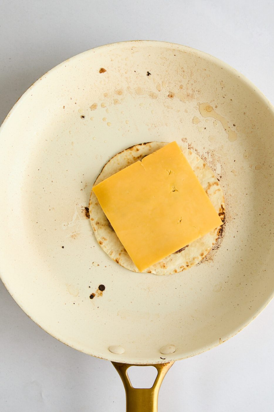 Adding a piece of cheese on top of the meat. 