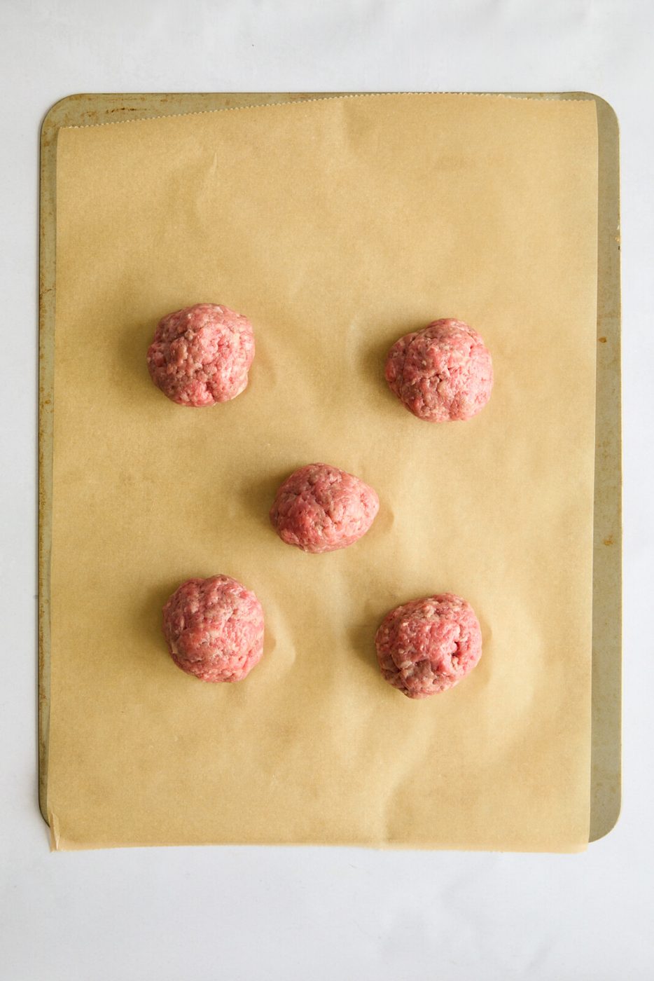 5 balls equally divided on a baking sheet lined with parchment paper.
