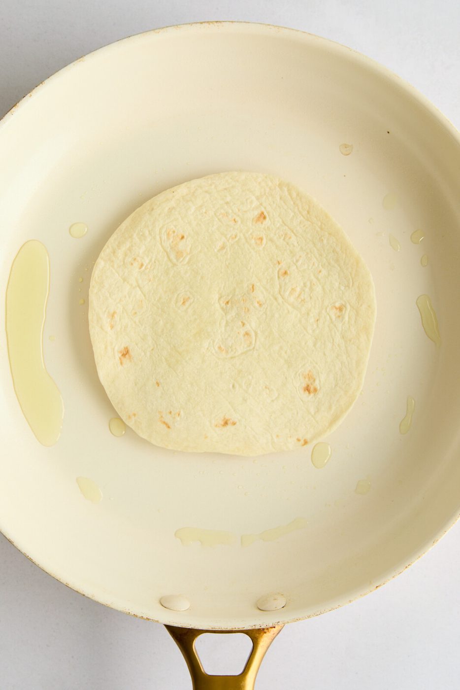 A photo of the tortilla flipped meat side down in the pan. 