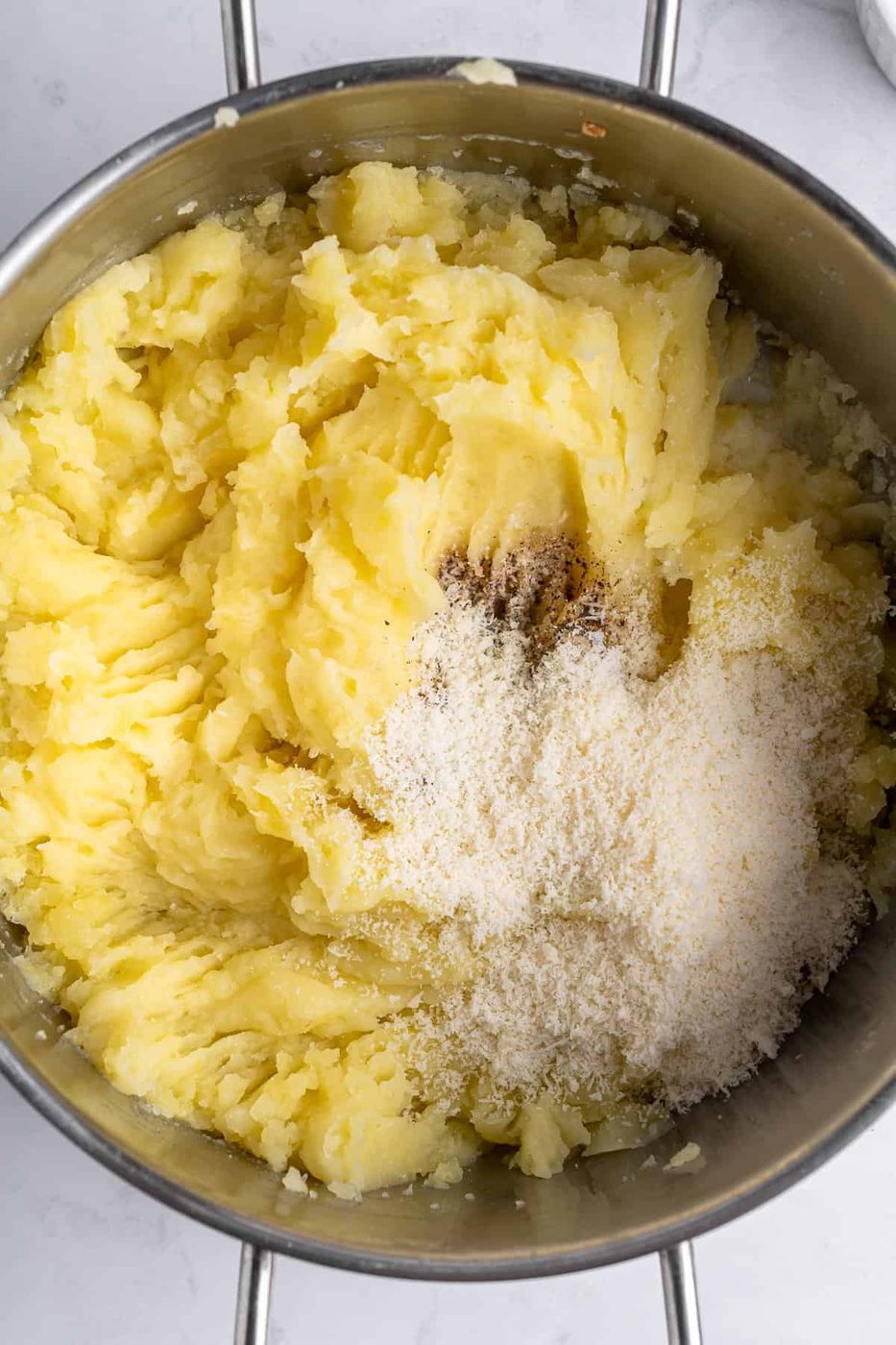 A bowl of mashed potatoes, salt and various spices. 