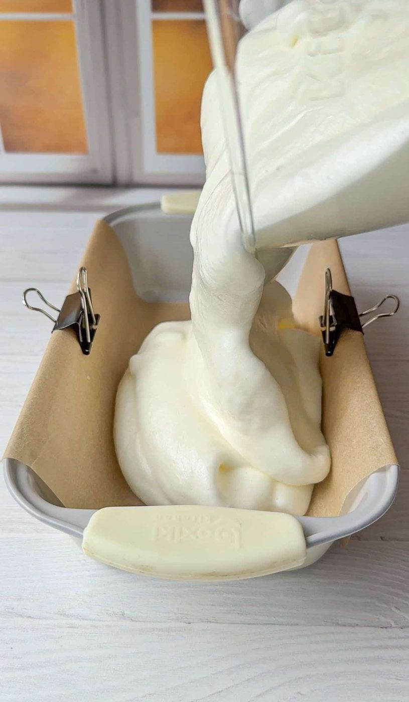 The Cloud Bread batter is being poured into a parchment lines bread pan.