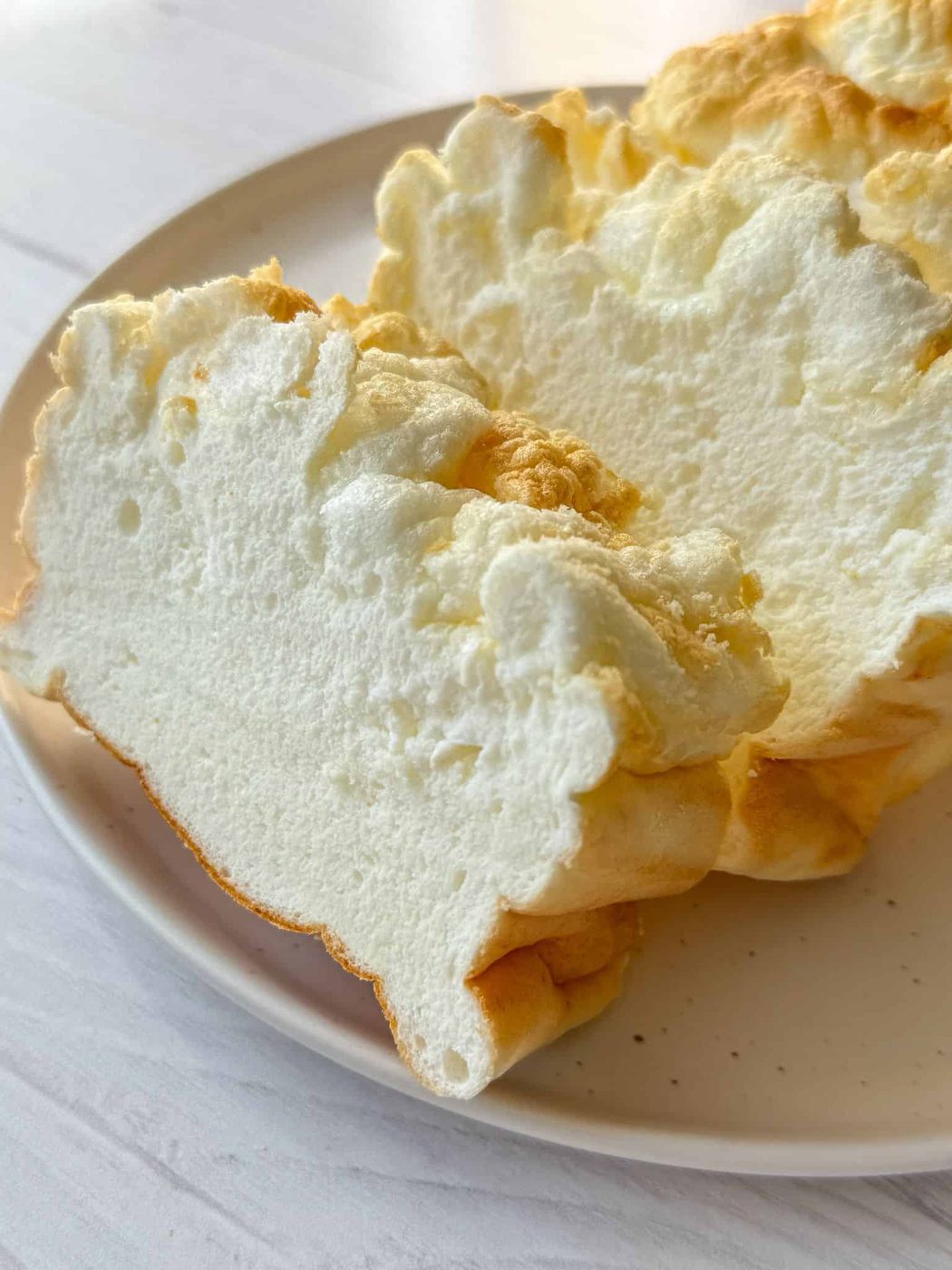 A photo featuring the best Cloud Bread. The bread is freshly baked and sliced on a plate.