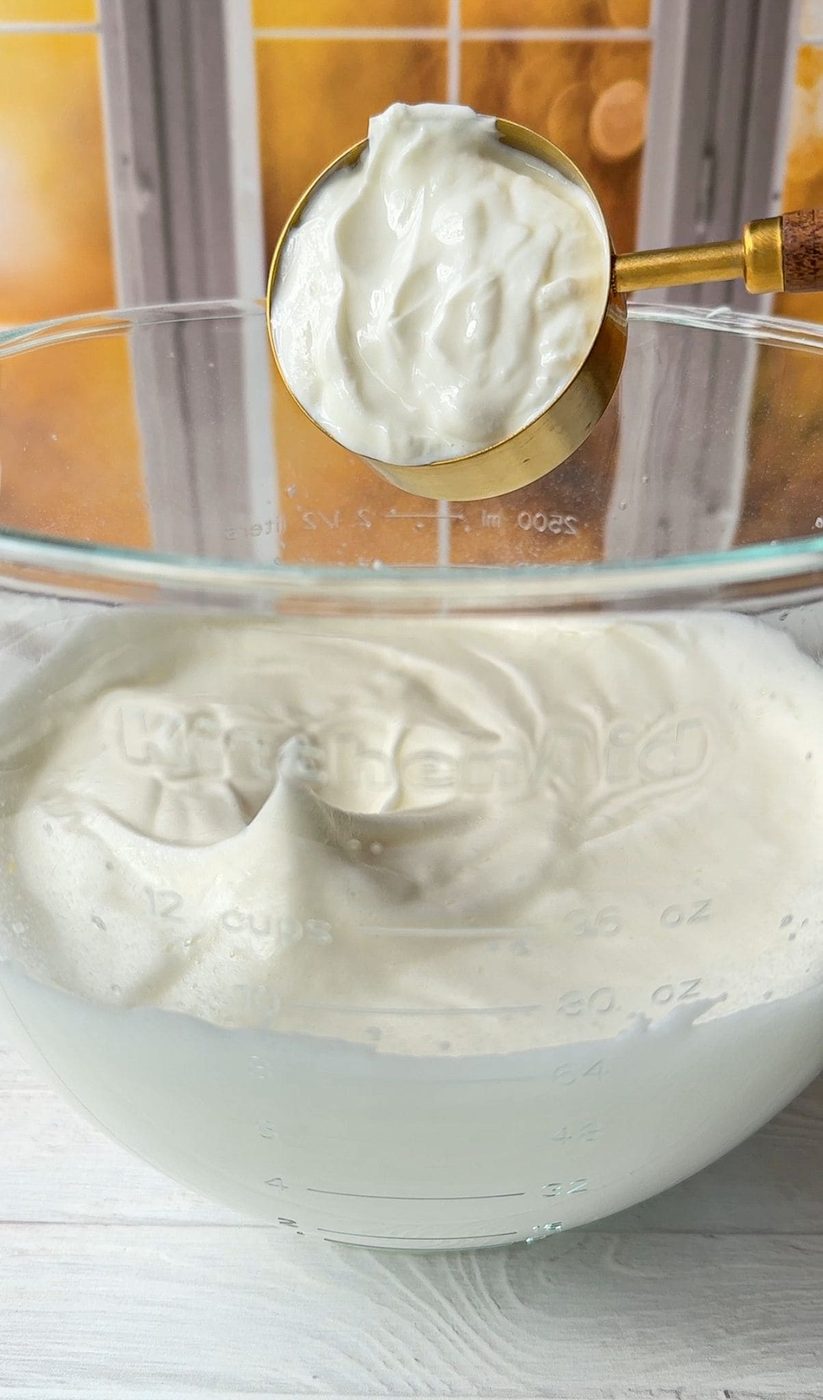 The yogurt is being added to the whipped egg whites.