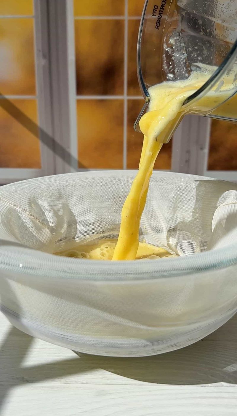 pouring the juice from the blender into a nut milk bag