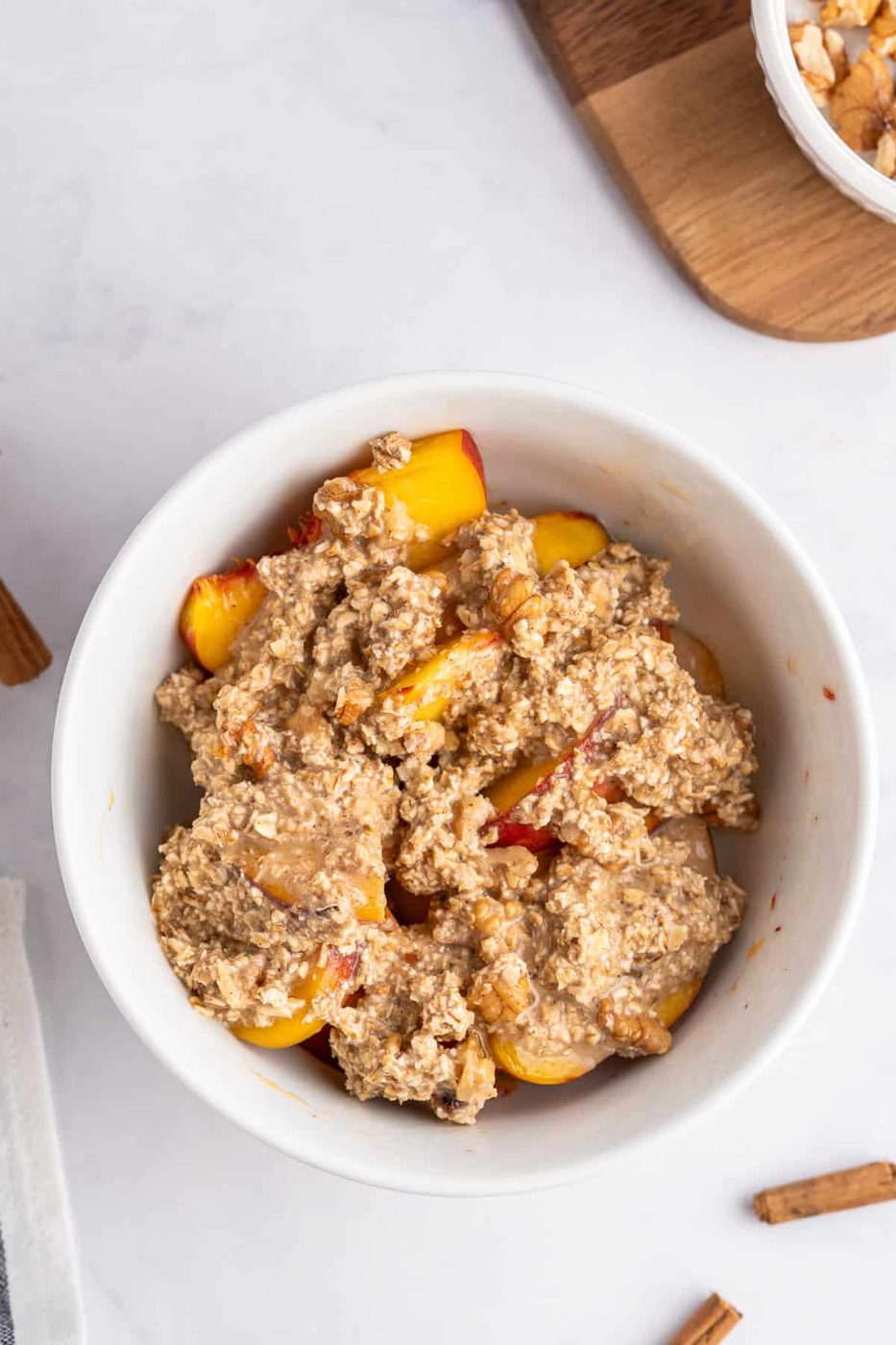 a photo featuring adding the crisp topping on top of the fresh peaches in the ramekin 