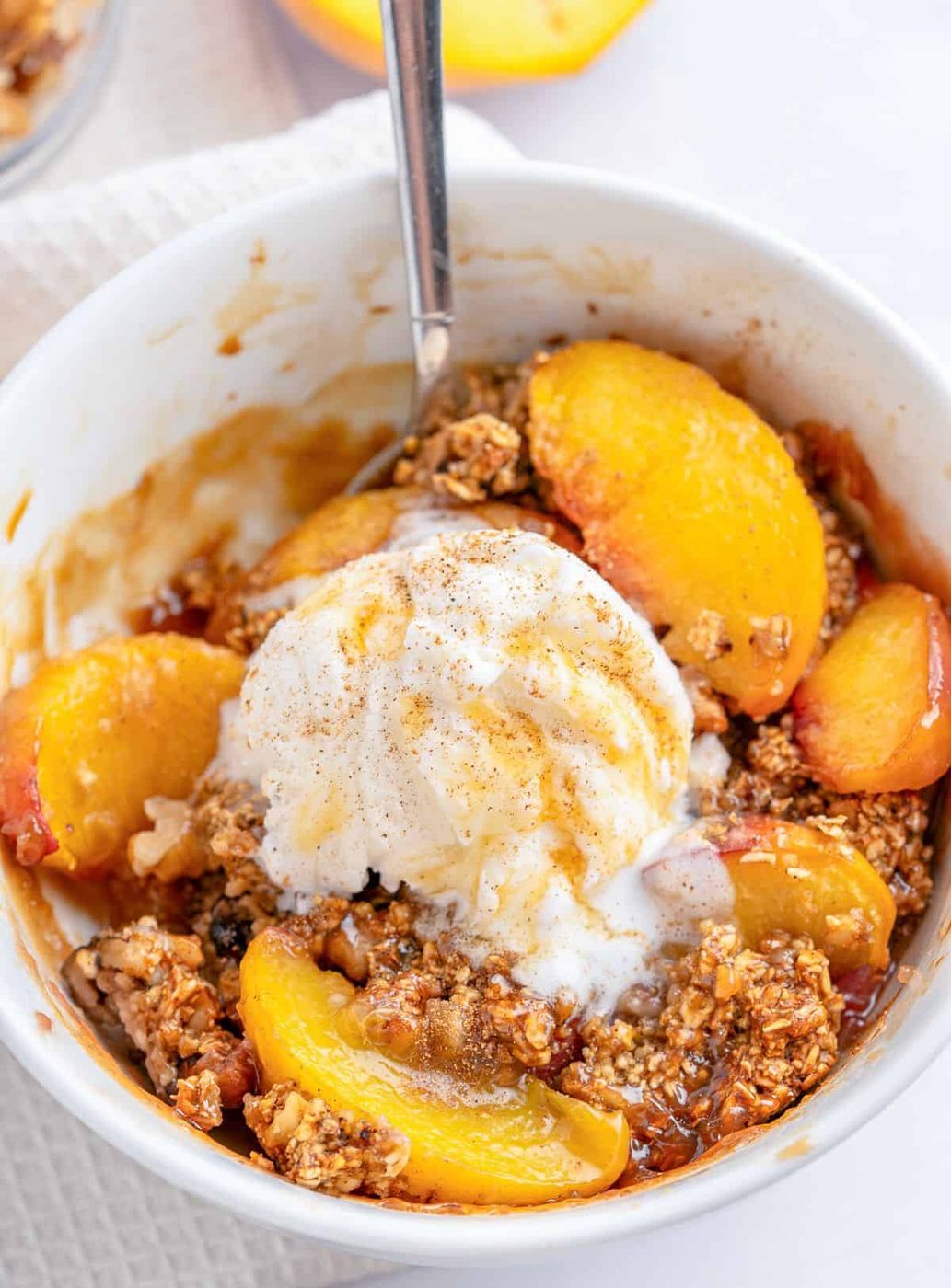 The finished recipe in a ramekin with baked peaches and ice cream on top.