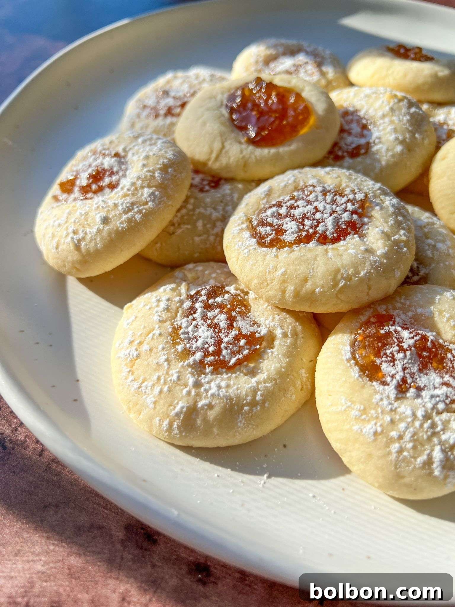Delicious Lemon Cheesecake Thumbprint Cookies on a baking sheet, showcasing their golden edges and jam-filled centers.