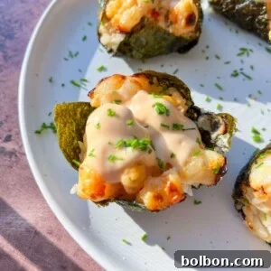 Close-up of Shrimp Sushi Cups baked to perfection, topped with a creamy sauce and sprinkled with chopped herbs, served on a white plate.