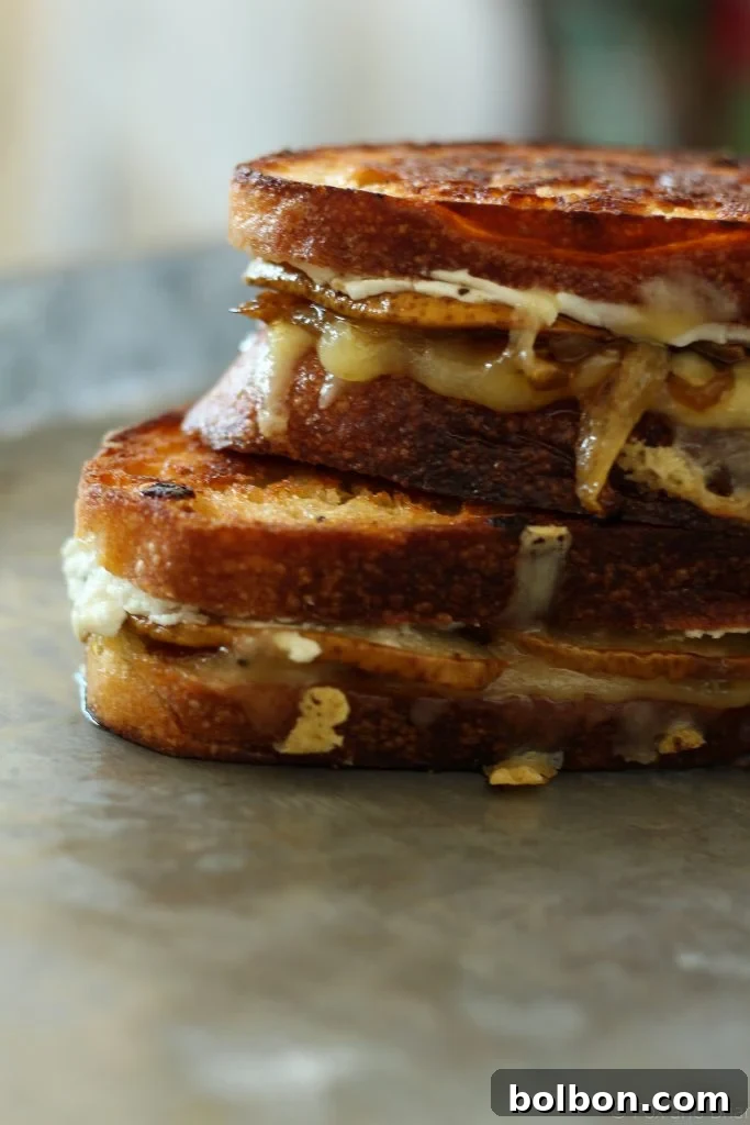 A glorious close-up of the Honey Roasted Pear, Goat Cheese, and Caramelized Onion Grilled Cheese, showcasing its oozing, melty perfection.