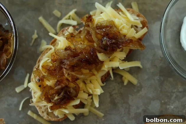 Building the grilled cheese: buttered bread topped with a generous layer of shredded sharp cheddar cheese.