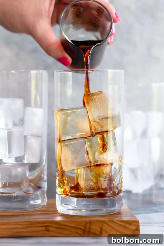 A close-up view of a glass filled with homemade Pumpkin Cream Cold Brew, highlighting the smooth transition from dark cold brew to the light, airy pumpkin cream on top, ready for a refreshing sip.