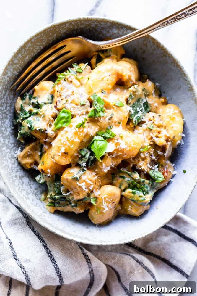 Creamy Pumpkin and Sausage Gnocchi: A comforting 30-minute one-pan dinner. A bowl of creamy pumpkin sausage gnocchi with fresh kale, ready to be enjoyed.