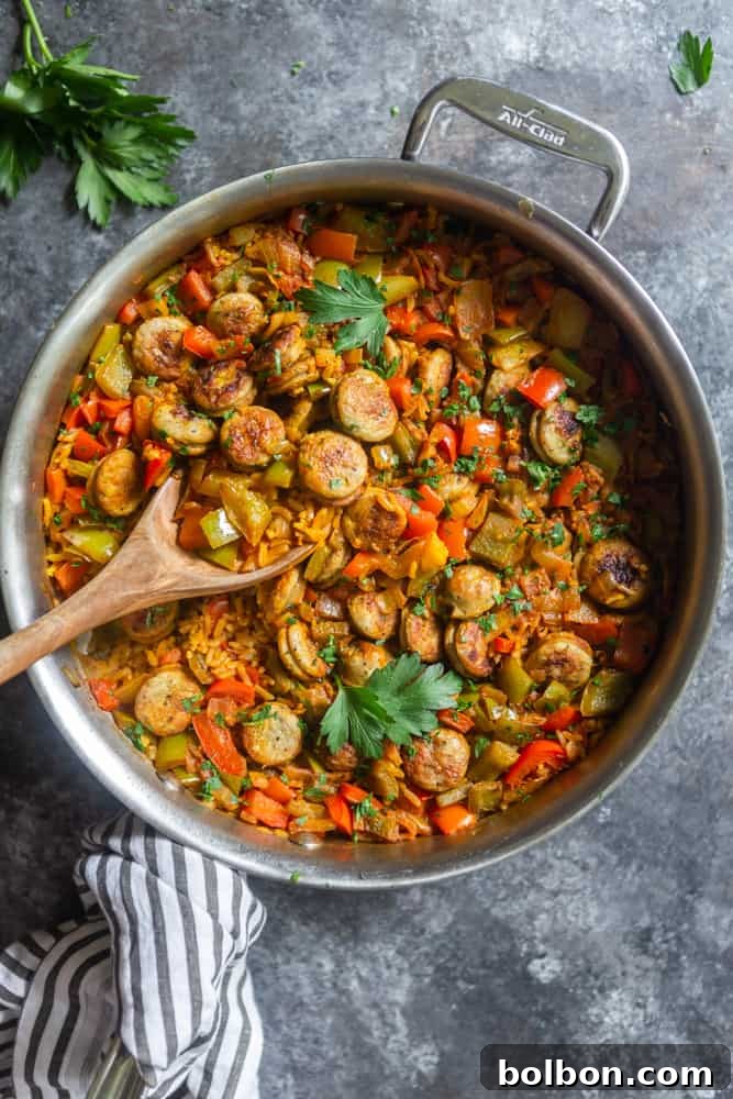Skillet with browning sausage, colorful bell peppers, and onions, the aromatic base for the One-Pot Sausage and Rice Skillet