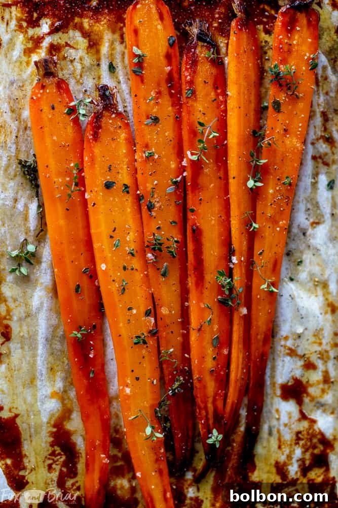 Honey Roasted Carrots in a white serving bowl, garnished with herbs