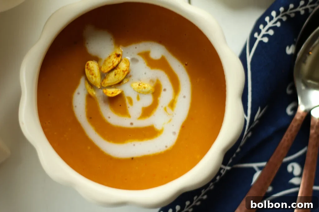 This vegan and gluten free soup is so warm and filling. Perfect for fall! A cozy bowl of Roasted Pumpkin Coconut Curry Soup, garnished with roasted pumpkin seeds.