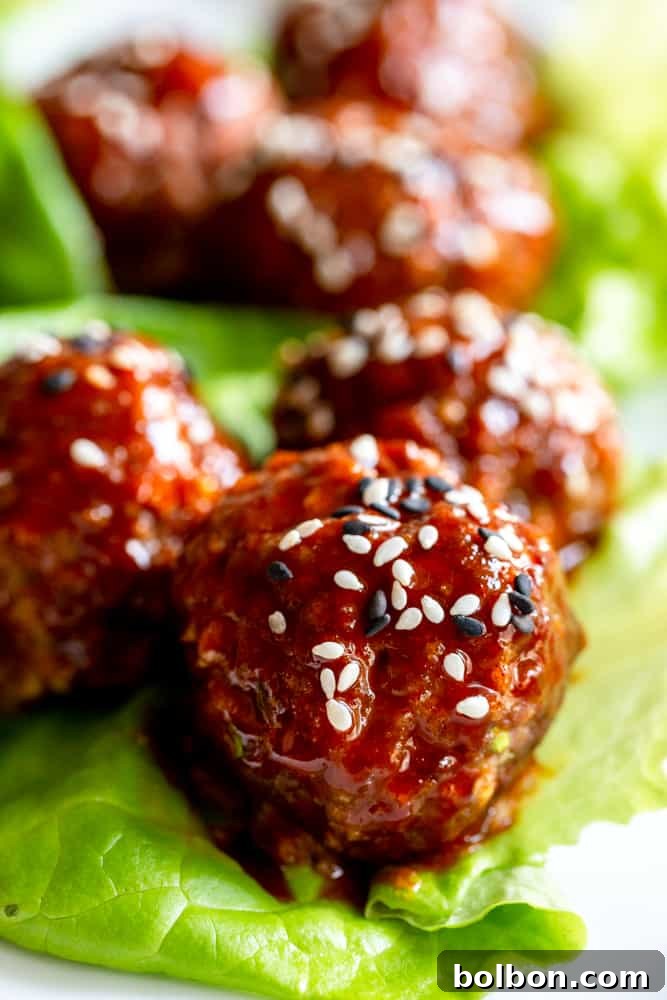 Korean Meatballs Made Easy 8 Several sweet and spicy Gochujang meatballs plated beautifully, garnished with sesame seeds and green onions.