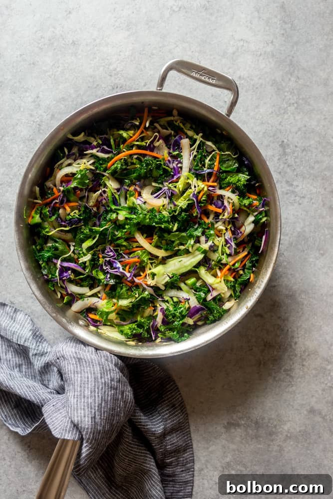 A large pan filled with the vibrant, cooked cabbage and kale mixture, ready to be combined with the ground meat and sauce for the Egg Roll in a Bowl
