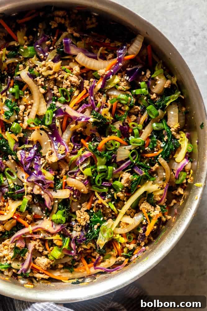 A close-up view of the perfectly cooked Egg Roll in a Bowl mixture in a large pan, steaming and ready to be served, showcasing its rich texture and vibrant colors