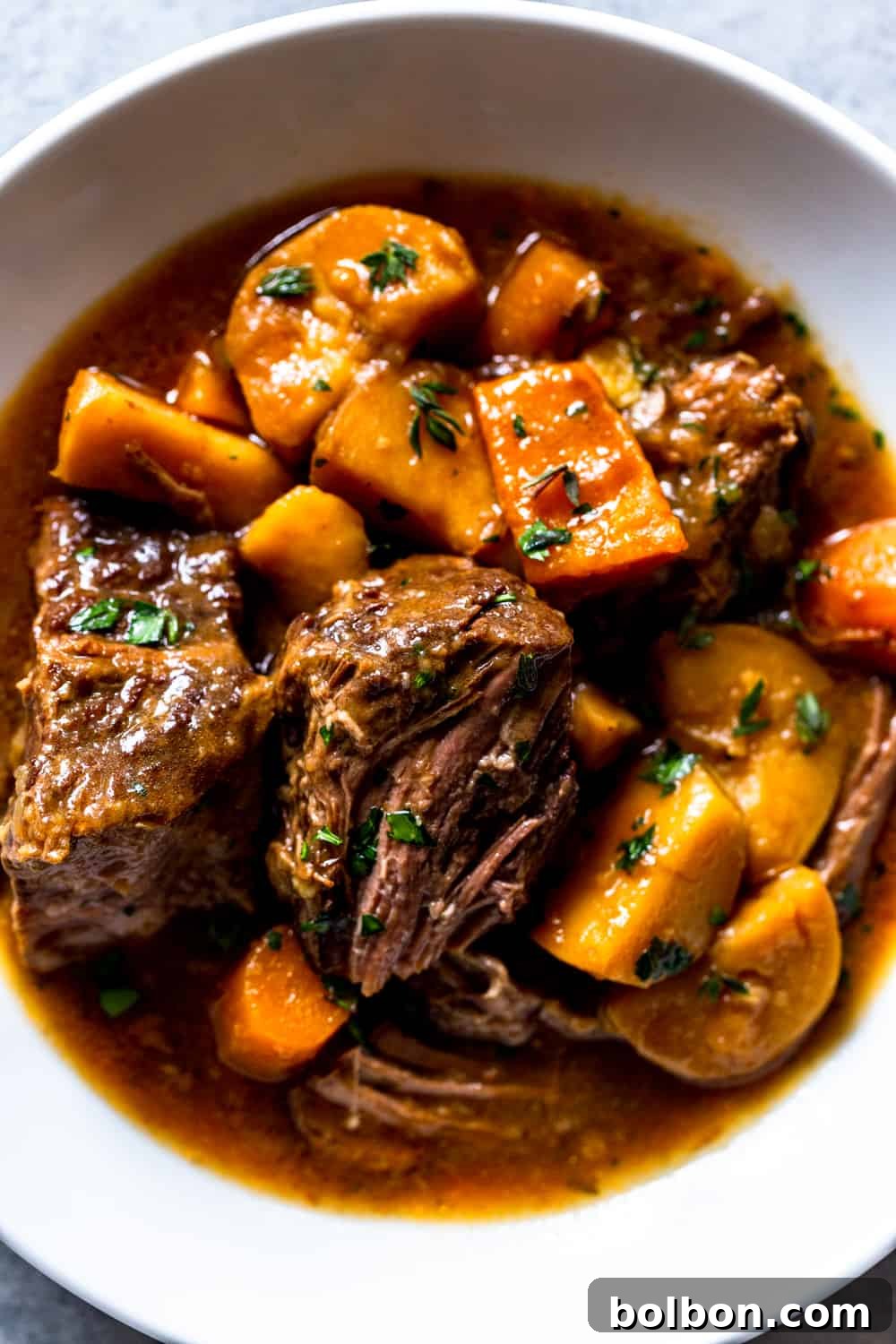 A bowl of Slow Cooker Irish Beef Stew served with a side of crusty bread and a drink.