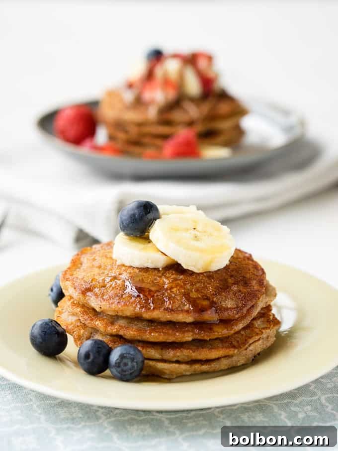 Stack of vegan banana pancakes with syrup and fresh fruit