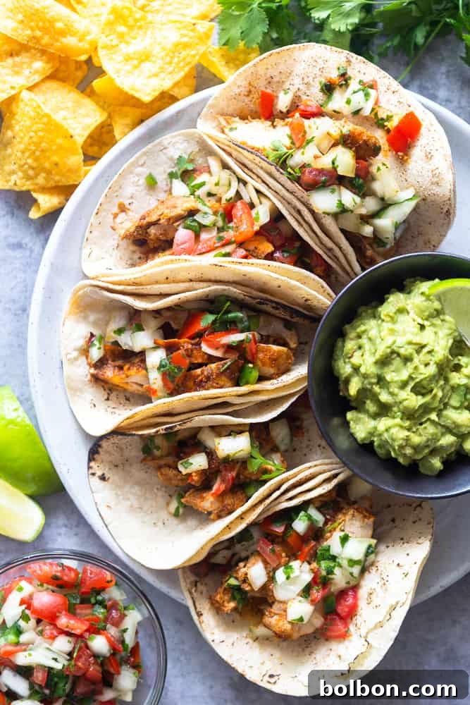 A vibrant plate of chili lime chicken tacos, served alongside crispy tortilla chips and a fresh bowl of pico de gallo, inviting you to a delightful Mexican-inspired meal.