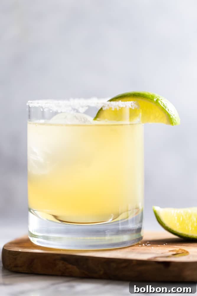 Effortless Homemade Margarita Recipe 4 A close-up of a classic margarita in a clear, salt-rimmed glass, garnished with a vibrant lime wedge, ready to be enjoyed.