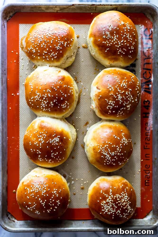 Freshly baked homemade hamburger buns on a cooling rack, golden brown and fluffy, ready to be served with burgers.