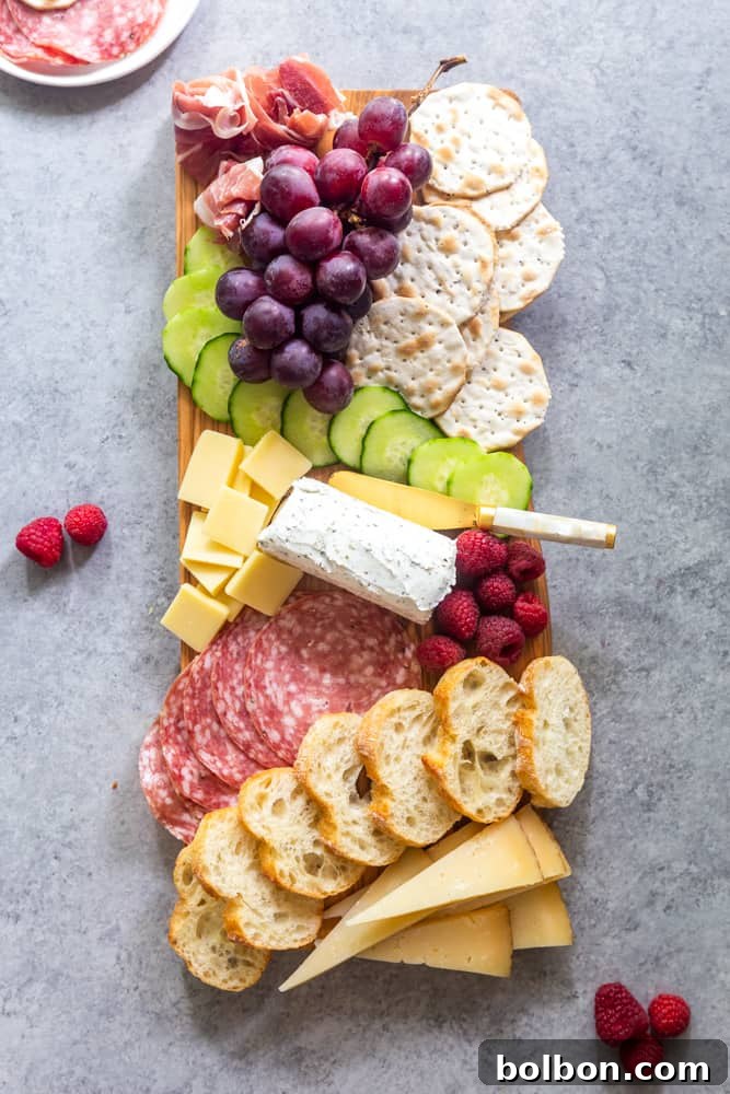 A simple summer snacking board featuring cheese, salami, grapes, and crackers