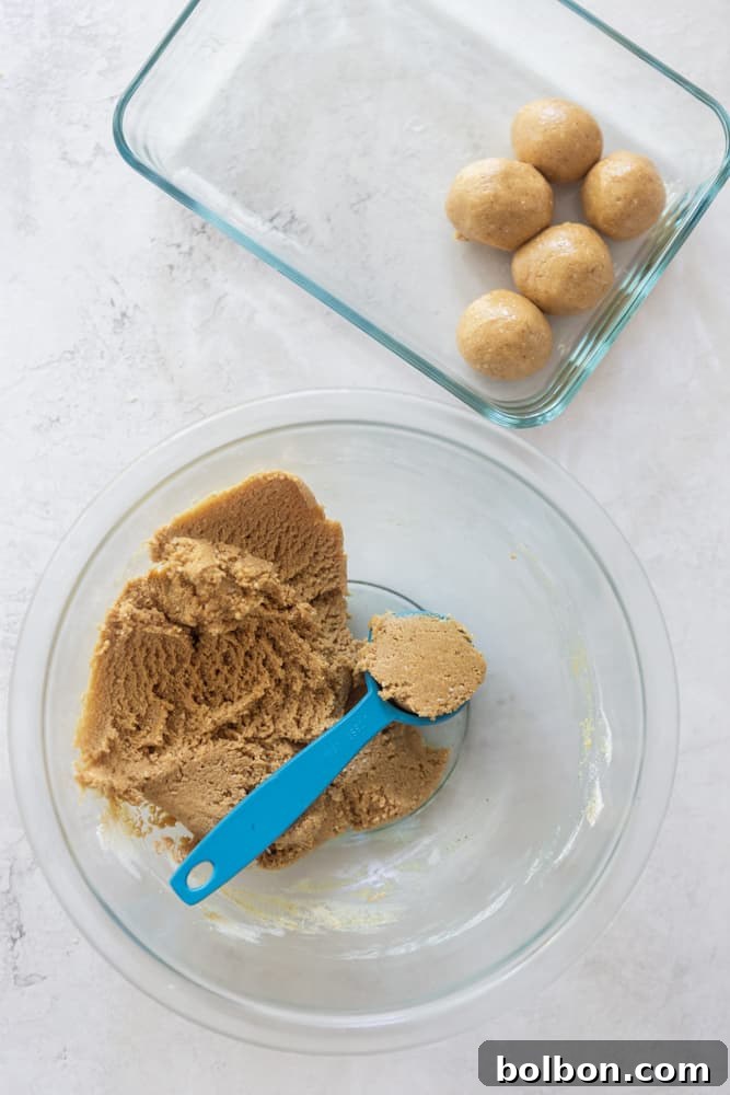 Honey-Sweetened Peanut Butter Power Bites 5 Close-up of peanut butter energy balls dough in a bowl, with a measuring spoon, highlighting the perfect consistency for rolling