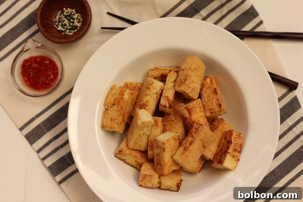 Perfect Tofu Secrets 3 Extra-firm tofu block, perfect for stir-fries and crispy preparations, sitting next to a cutting board.