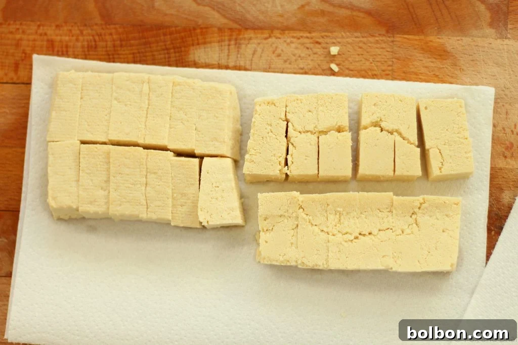 Perfect Tofu Secrets 10 Slices of tofu laid out on paper towels, covered with another sheet, and gently pressed to remove final surface moisture.