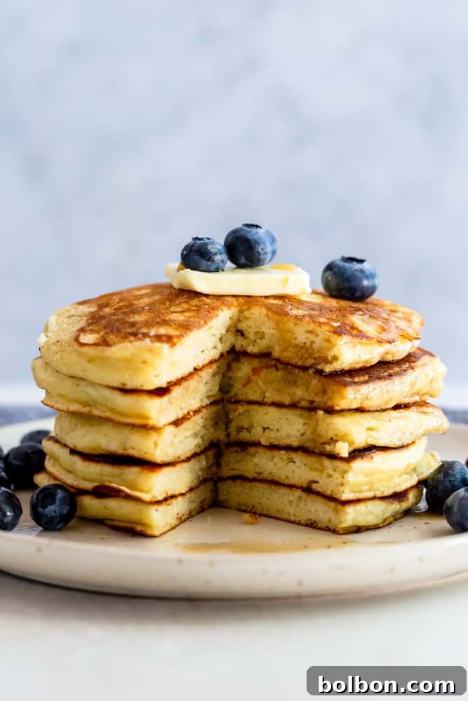 Perfectly Fluffy Buttermilk Pancakes 5 A perfectly cooked stack of fluffy buttermilk pancakes with a single wedge removed, highlighting their inviting texture and readiness to be savored.