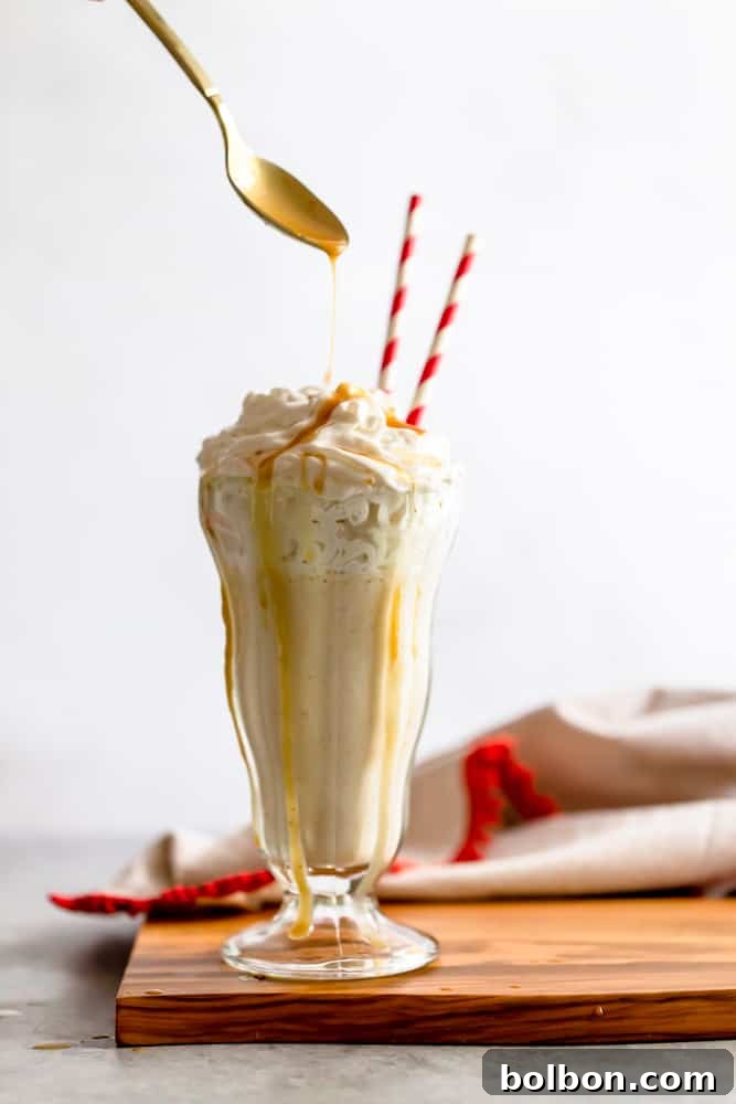 Creamy Coconut Cashew Vegan Milkshake topped with whipped cream and caramel drizzle in a tall glass.