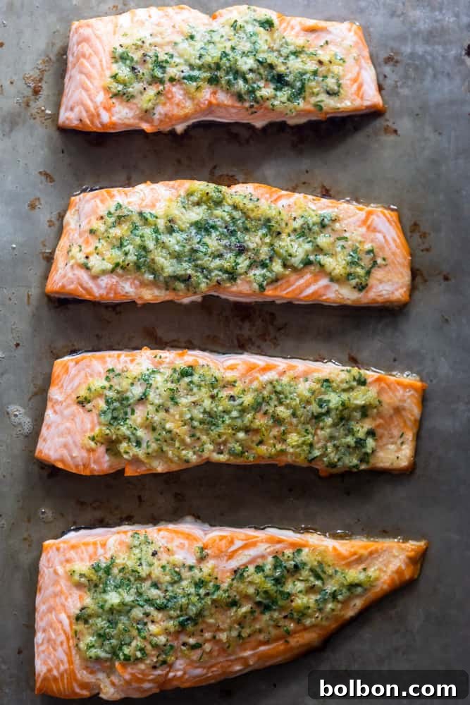 Freshly baked salmon fillets resting on a baking sheet, glistening with garlic butter and ready to serve.