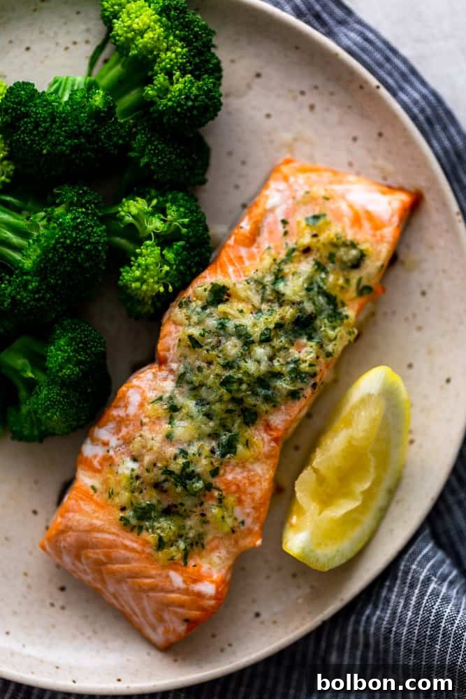 Cooked salmon fillet on a white plate, served alongside roasted broccoli, showcasing a complete and healthy meal.