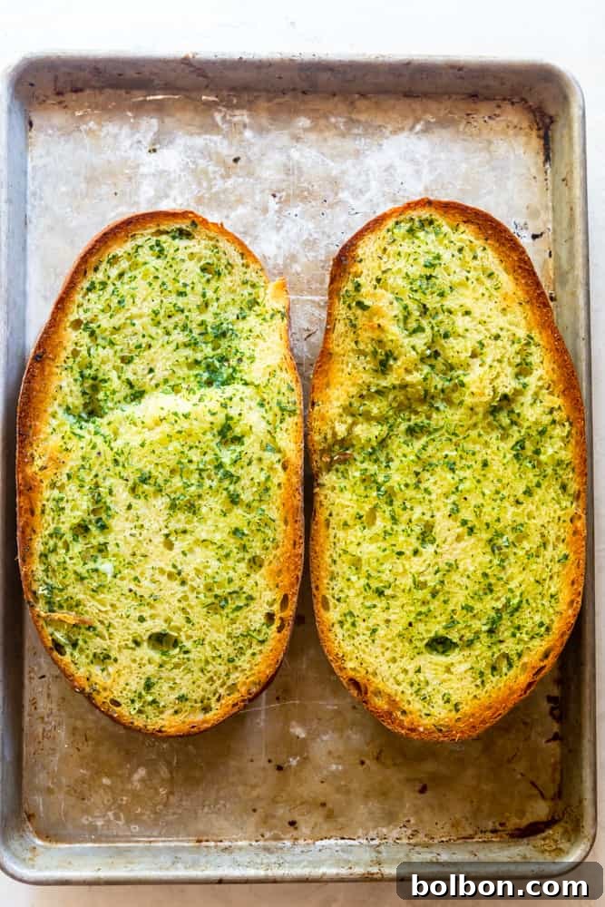 The Ultimate Easy Garlic Bread 5 Garlic bread with garlic butter spread, placed on a baking sheet, ready to go into the oven