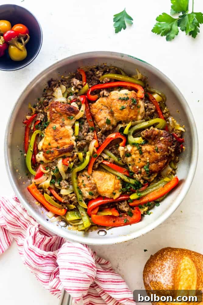 Chicken Scarpariello cooking in a large frying pan on the stovetop, showing the chicken, sausage, and vegetables simmering in the sauce.