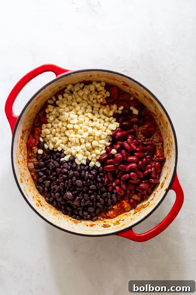 One-Pot Wonder Taco Soup 4 Close-up shot of black beans, kidney beans, and frozen corn kernels nestled within a vibrant red Dutch oven, ready to be simmered into a delicious taco soup.