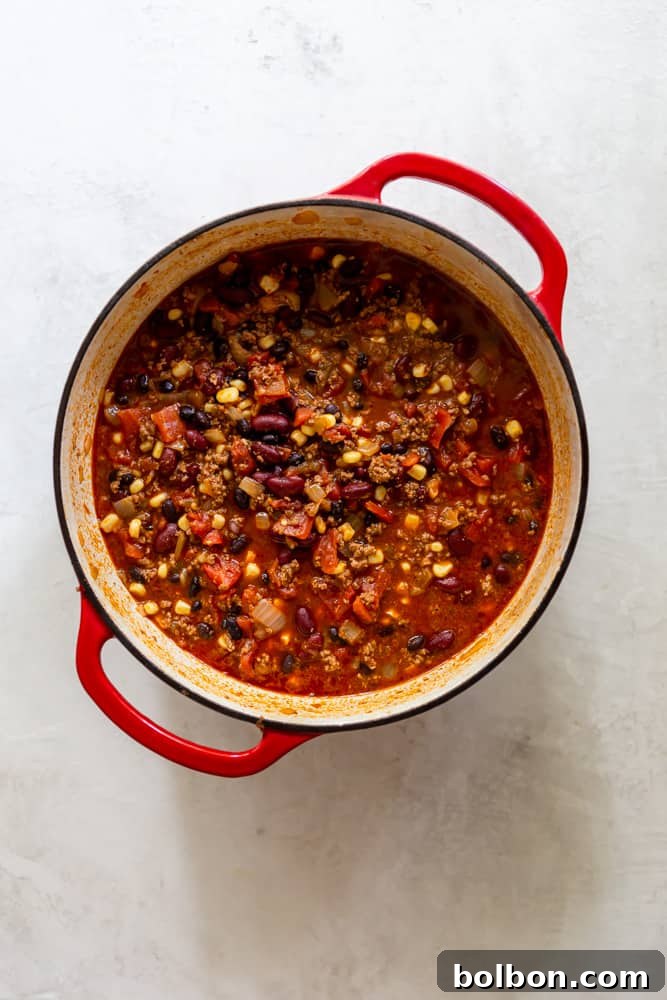 One-Pot Wonder Taco Soup 5 A large, vibrant red Dutch oven filled to the brim with a rich, steaming taco soup, showcasing its hearty ingredients like ground beef, beans, corn, and tomatoes, promising a comforting meal.