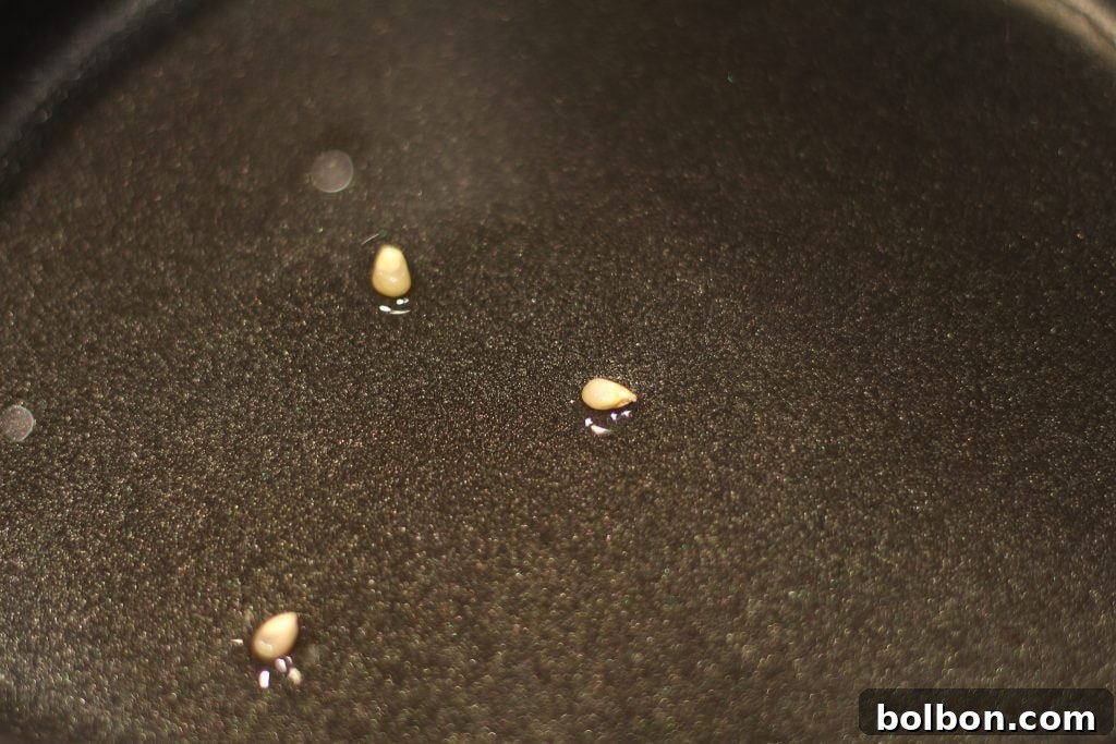 Close-up of popcorn kernels sizzling in oil, demonstrating the crucial 'three-kernel test' for ideal popping temperature.