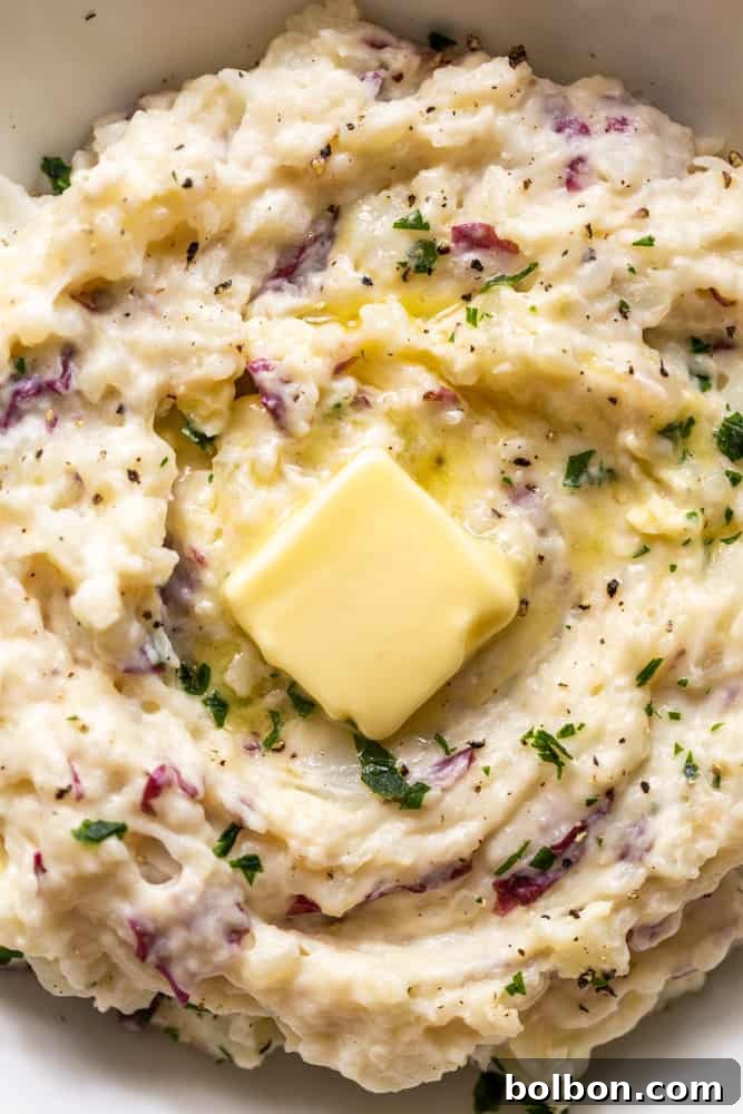 Close up of roasted garlic mashed potatoes with a pat of butter on top. 