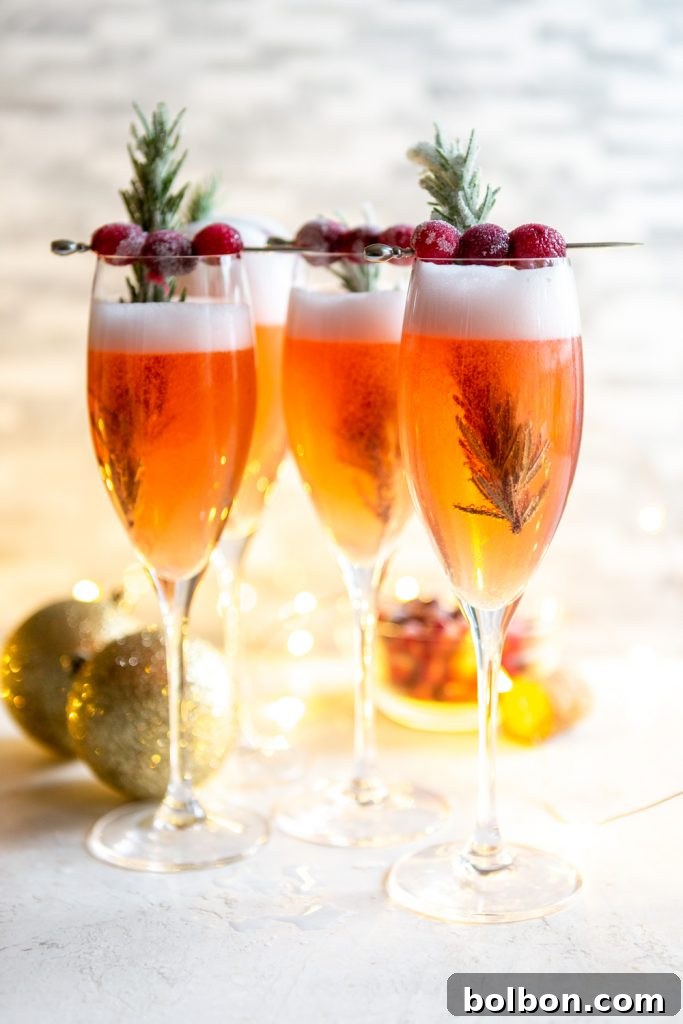 Cranberry mimosas in champagne flutes, garnished with cranberries and rosemary. 
