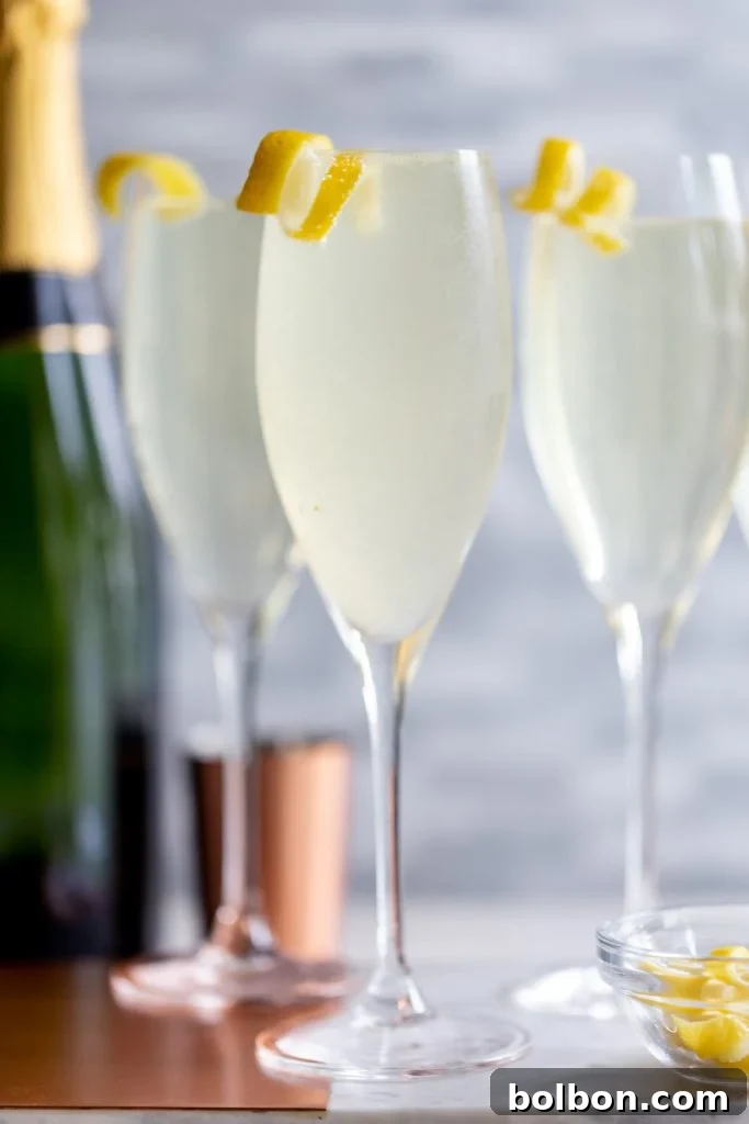 Three French 75 cocktails in champagne flutes, garnished with a lemon twist