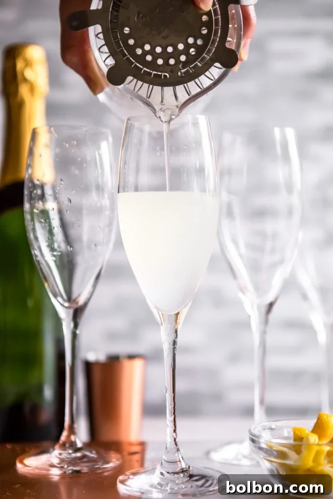 French 75 being poured from a cocktail strainer into a champagne flute