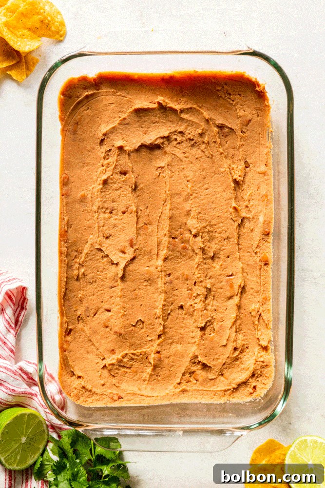 Seven Layer Fiesta Dip 3 GIF showing layers of the 7 layer dip - refried beans, sour cream, guacamole, salsa, cheese, olives, green onions and cilantro.