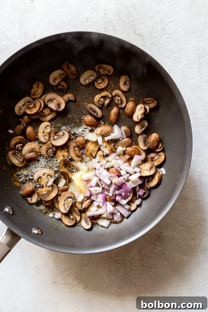 Dry-sauteed mushrooms, butter, and finely diced shallots cooking together, forming an aromatic base.