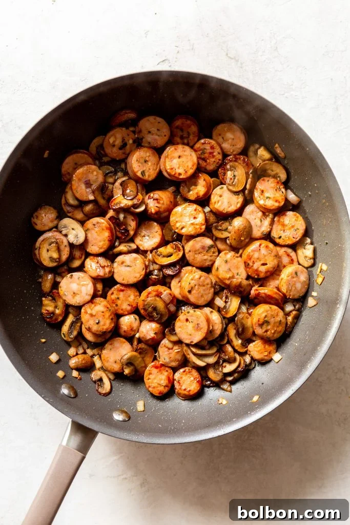 Sliced chicken sausage joining the mushrooms and shallots, adding lean protein to the pasta mix.