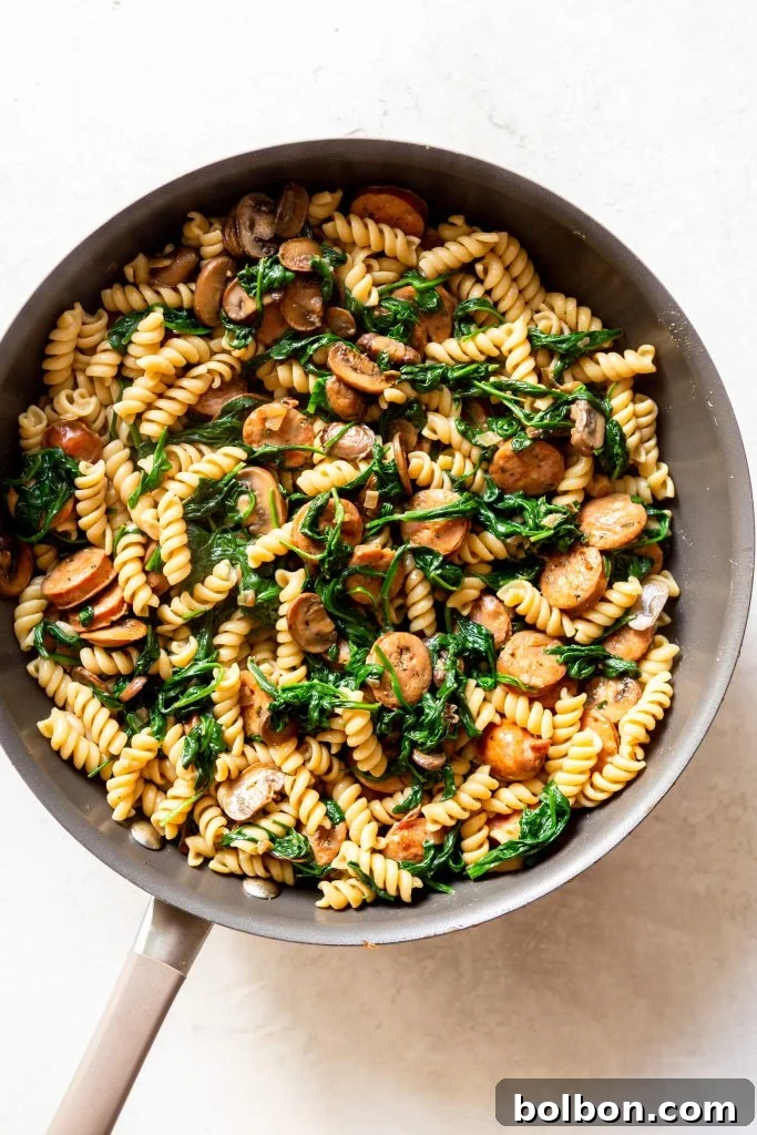 The fully wilted spinach, chicken sausage, and mushrooms beautifully combined in the pan.